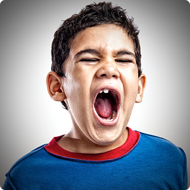 Stock image of small boy mouth open widely and shouting due to pain in teeth