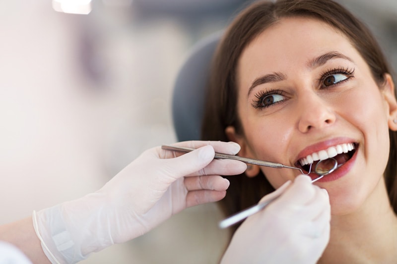 Stock image of a dentist hands with dental equipment working on a smiling patient